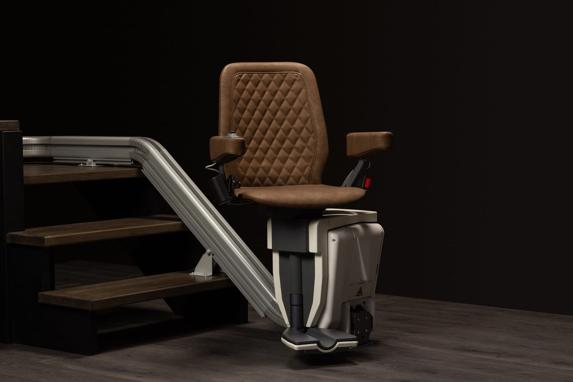 Brown upholstered stairlift chair beside carpeted stairs on a dark background