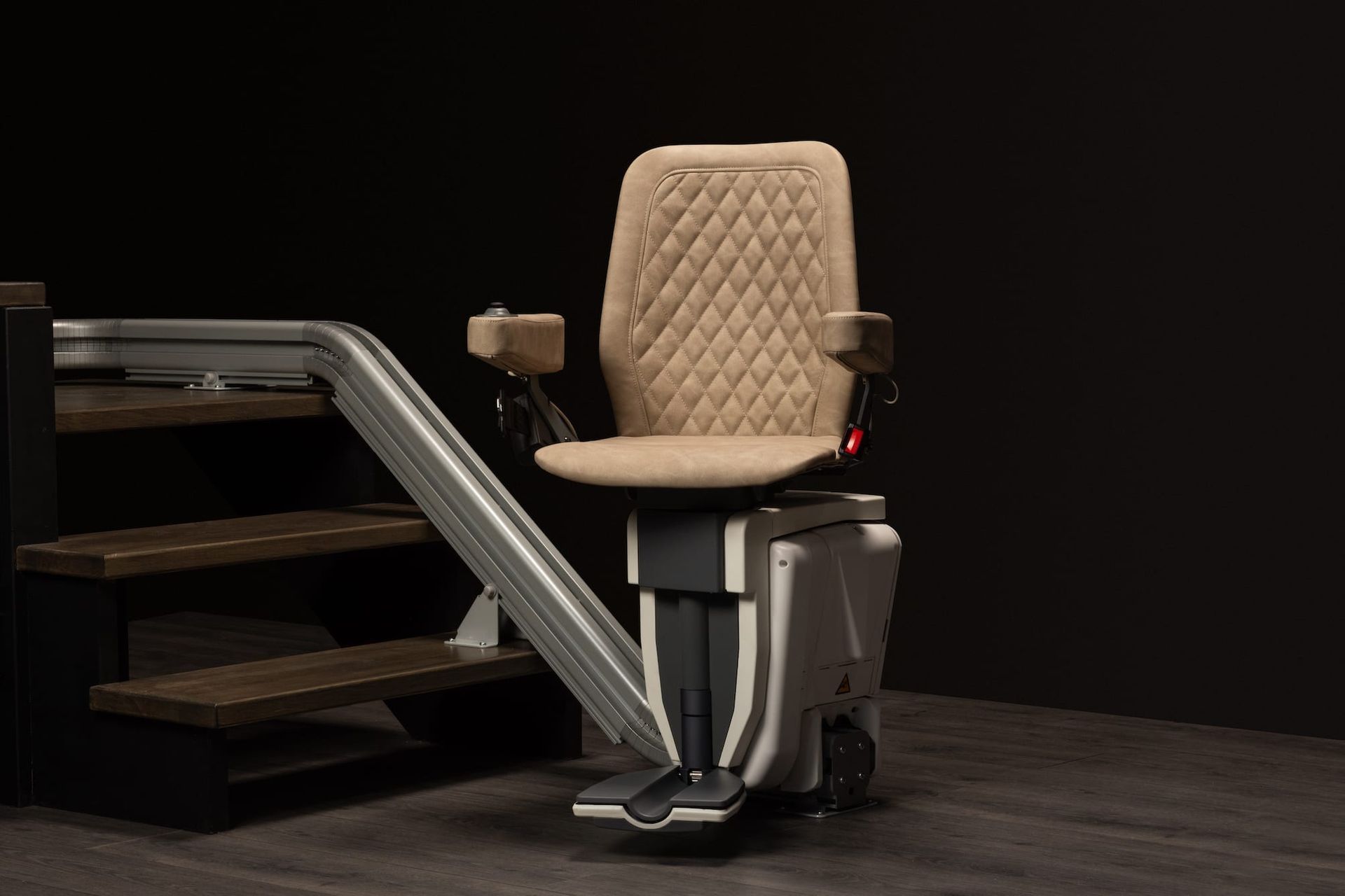 Beige stair lift chair on a wooden staircase in a dark room