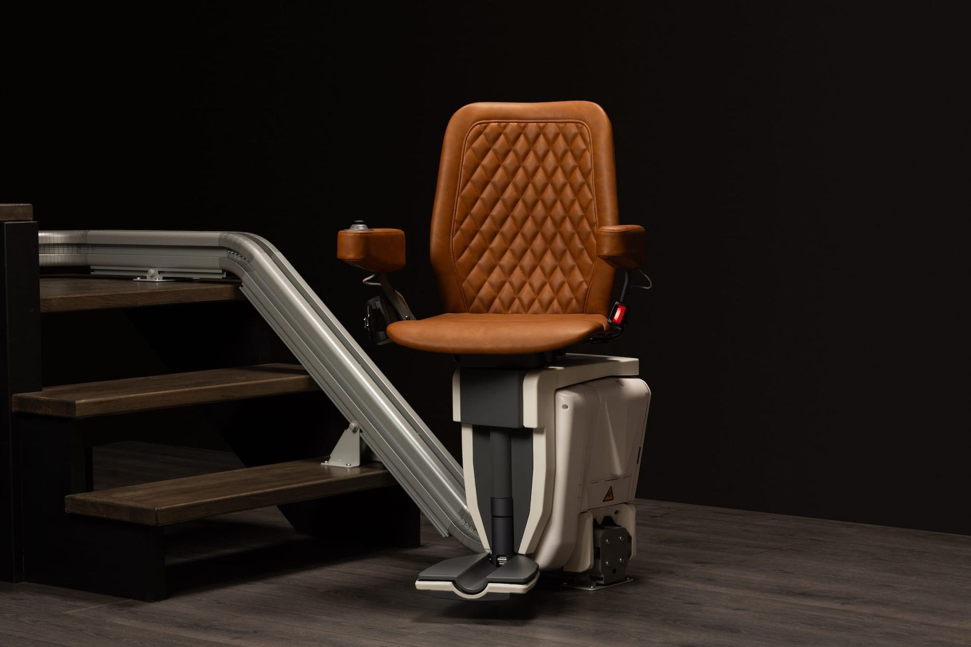 Orange stairlift chair mounted on a staircase in a dark room