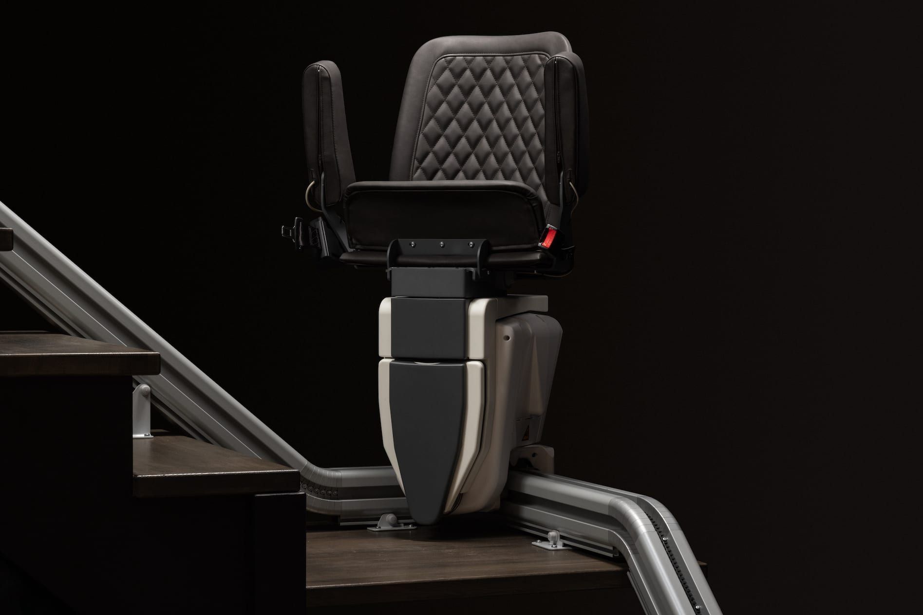 Compact stair-climbing chair lift on a staircase, shown in black and silver.