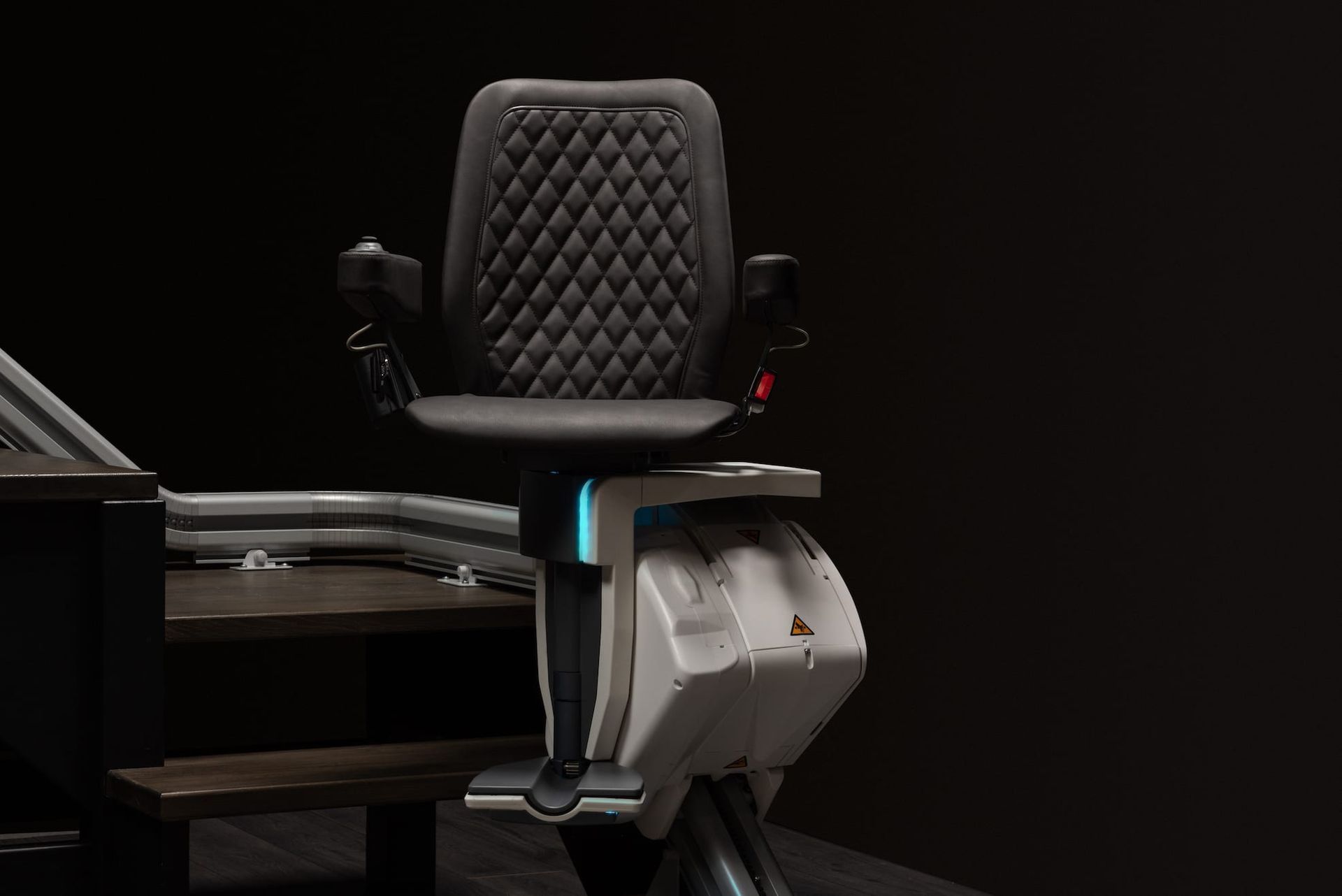 Black quilted office chair with armrests and blue accent lighting in a dark room