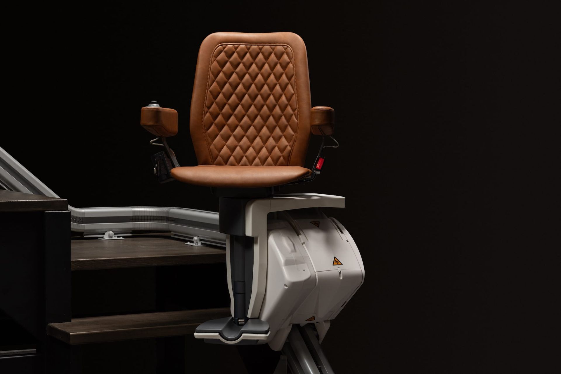 Brown tufted chair attached to a metallic machine in a dark setting