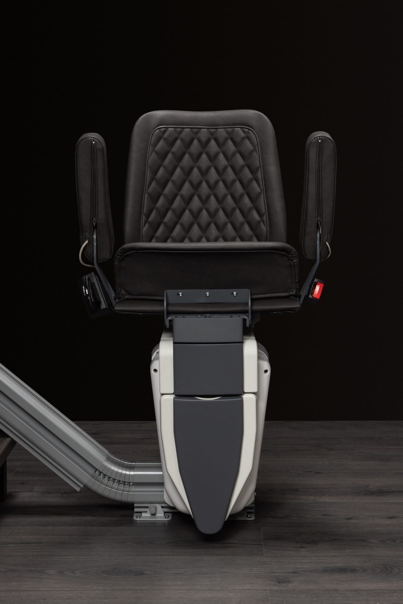 Black mobility scooter with quilted seat and side handles on a dark background.