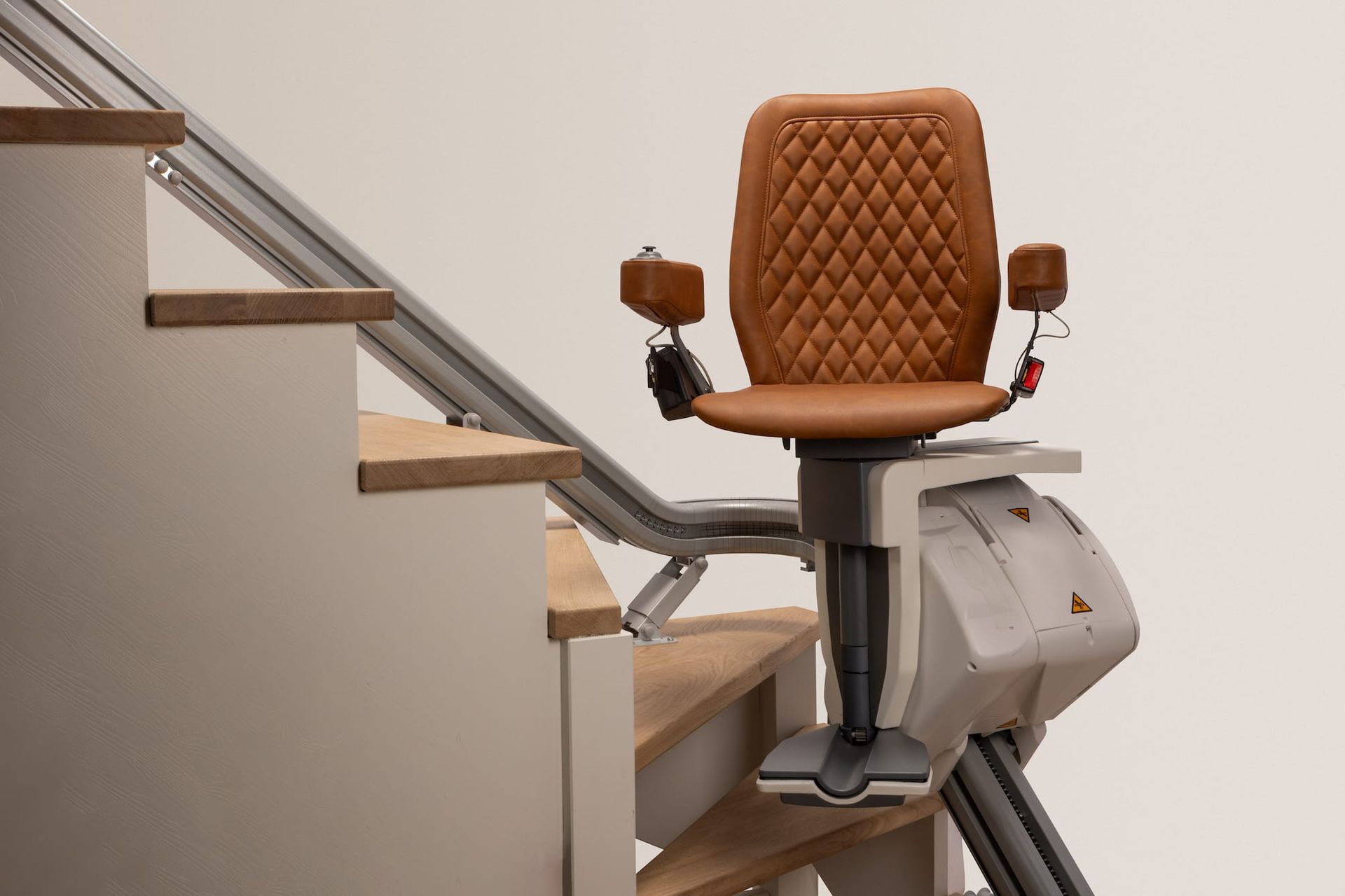 Stairlift chair with brown quilted seat mounted on indoor staircase