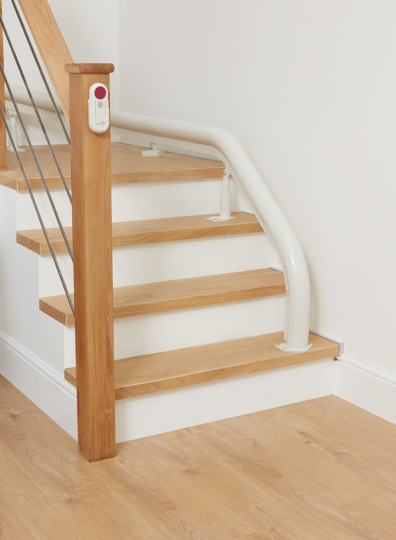 Wooden staircase with a white curved handrail and an emergency call button on a wooden post.