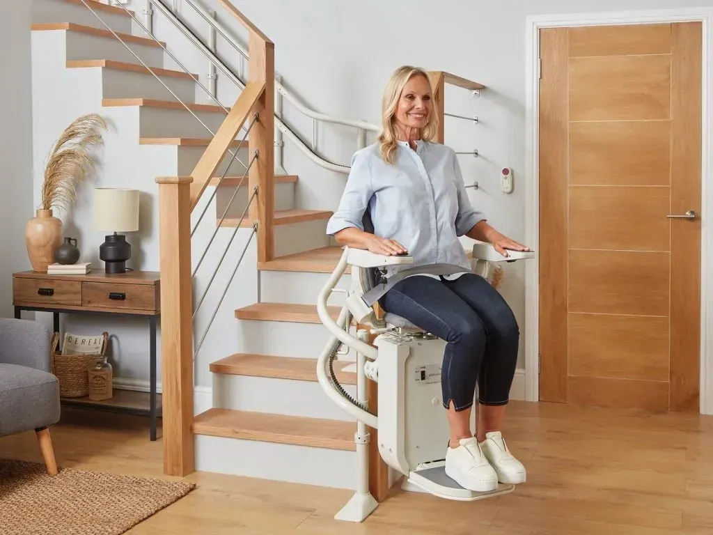 Beige stairlift footrest on light wood floor and step.