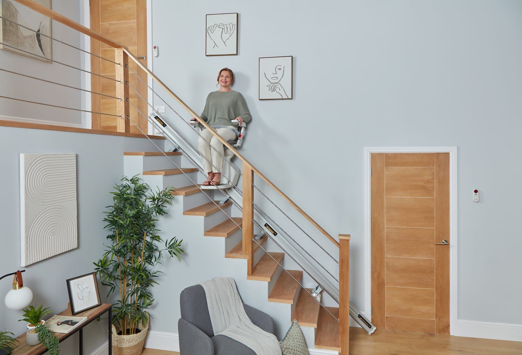 Person standing on wooden staircase in a bright modern living room with light blue walls.
