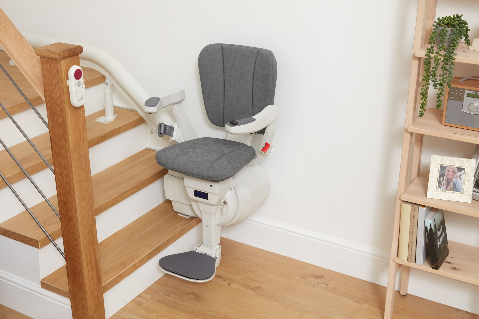 Stair lift with gray seat on wooden stairs, installed indoors.