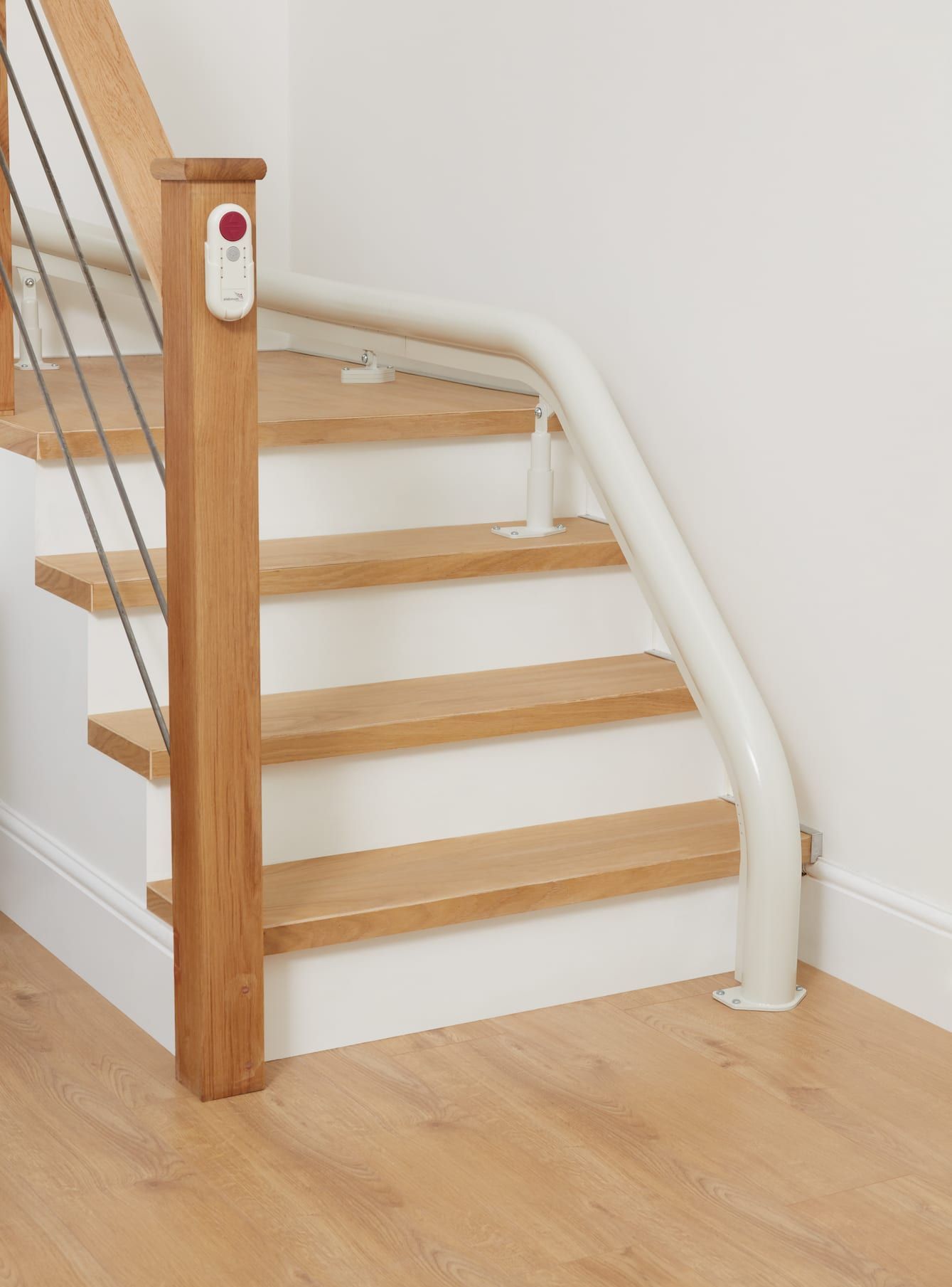 Staircase with wooden steps and a white handrail for accessibility, leading up to a landing.