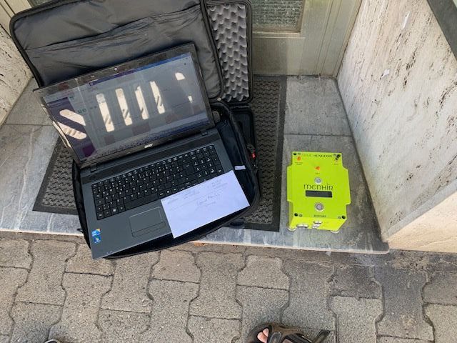 Ein Laptop steht neben einem gelben Kasten auf dem Boden.