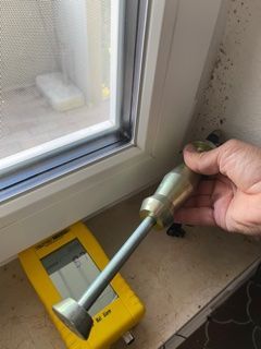 Eine Person hält ein Werkzeug vor einem Fenster.