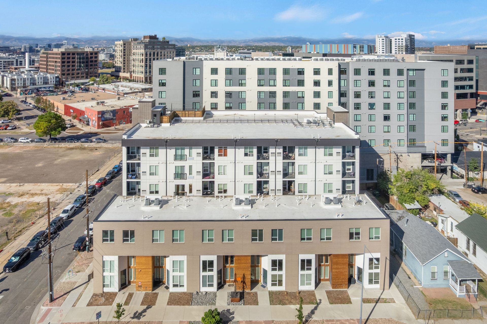 Aerial view of modern apartment buildings in an urban setting, with a blue sky and distant buildings.