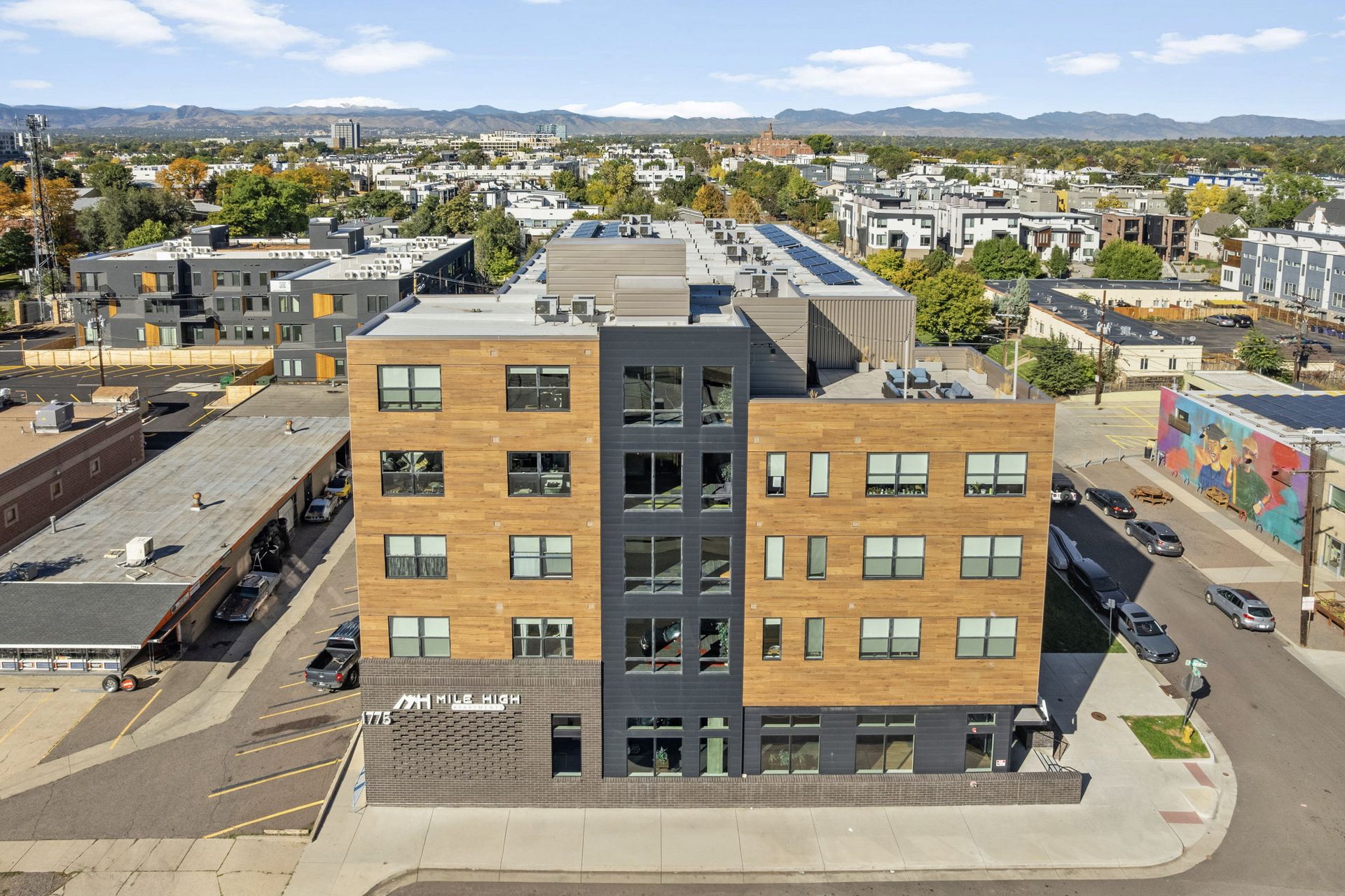 Modern apartment building with brick and dark siding against a city skyline.