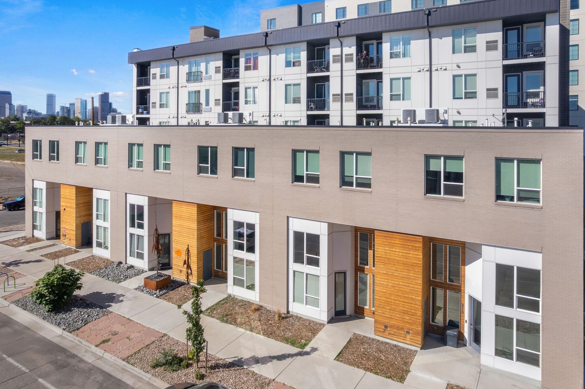 Modern apartment buildings with a city skyline in the background on a sunny day.