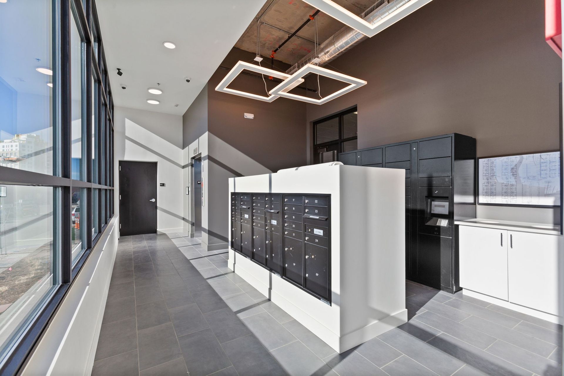 Apartment mailroom with mailboxes, counter, and modern lighting.