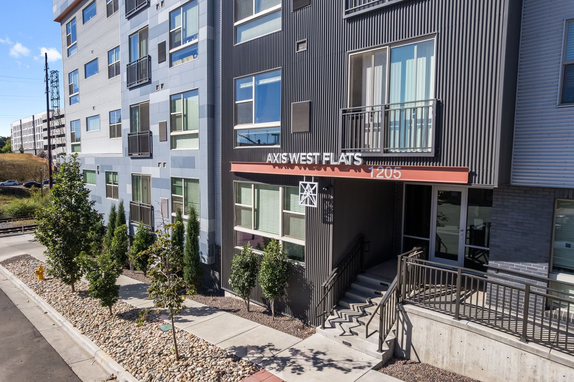 Entrance to 49 West Flats apartment building, with stairs, trees, and signage.
