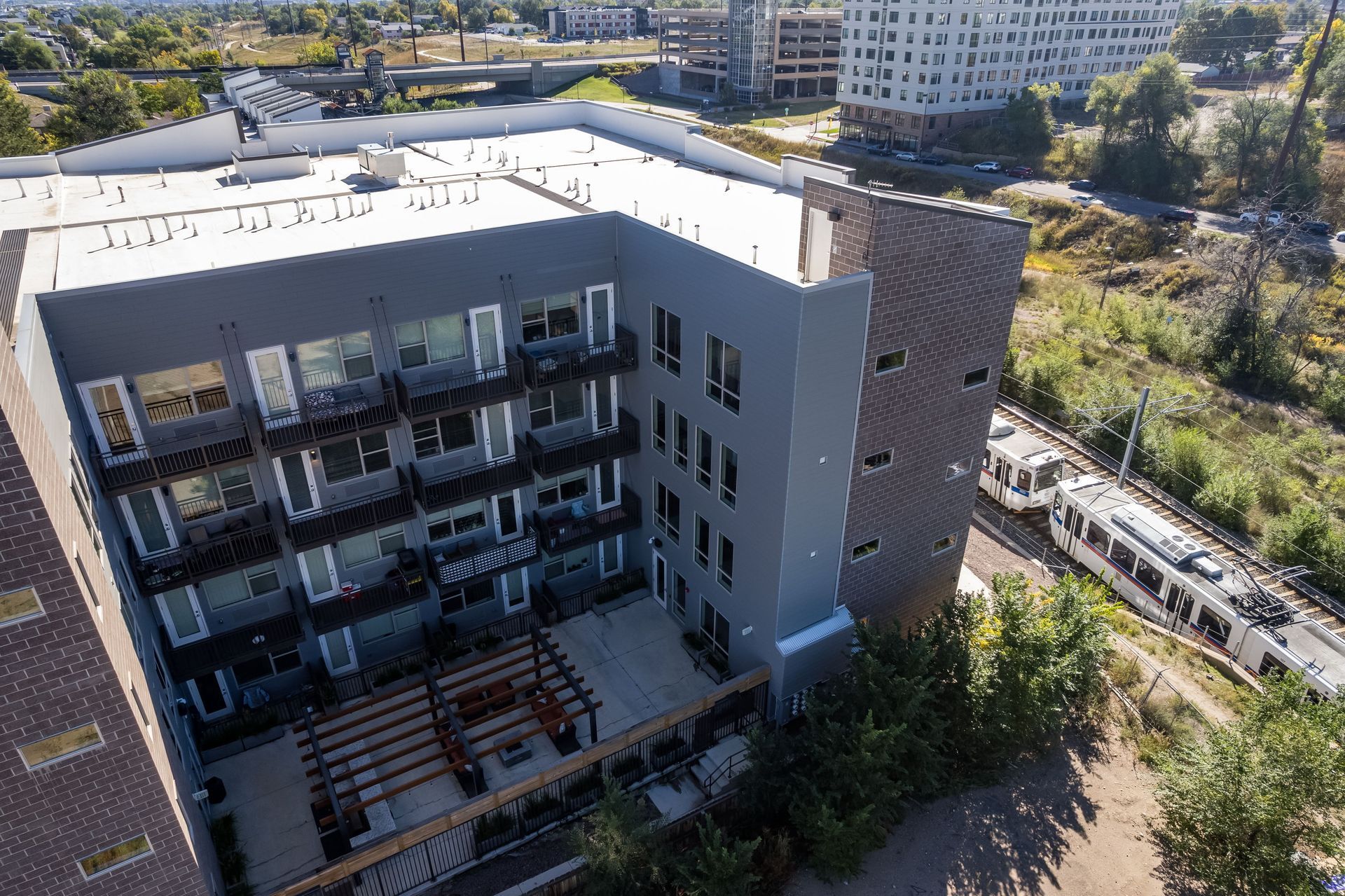 Apartment building next to train tracks, with train passing by.