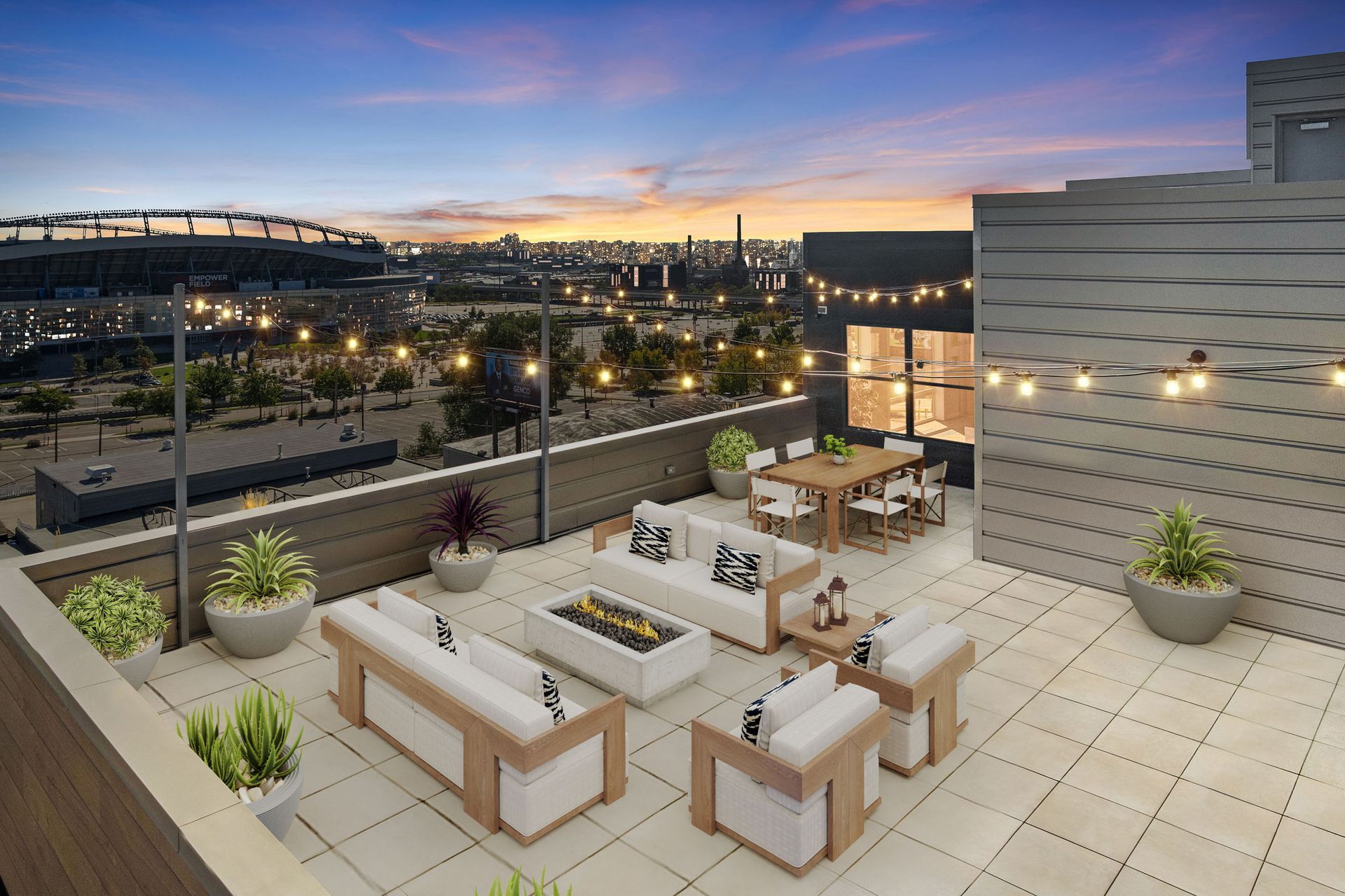 Rooftop patio with white furniture, fire pit, dining table, string lights, city skyline at dusk.