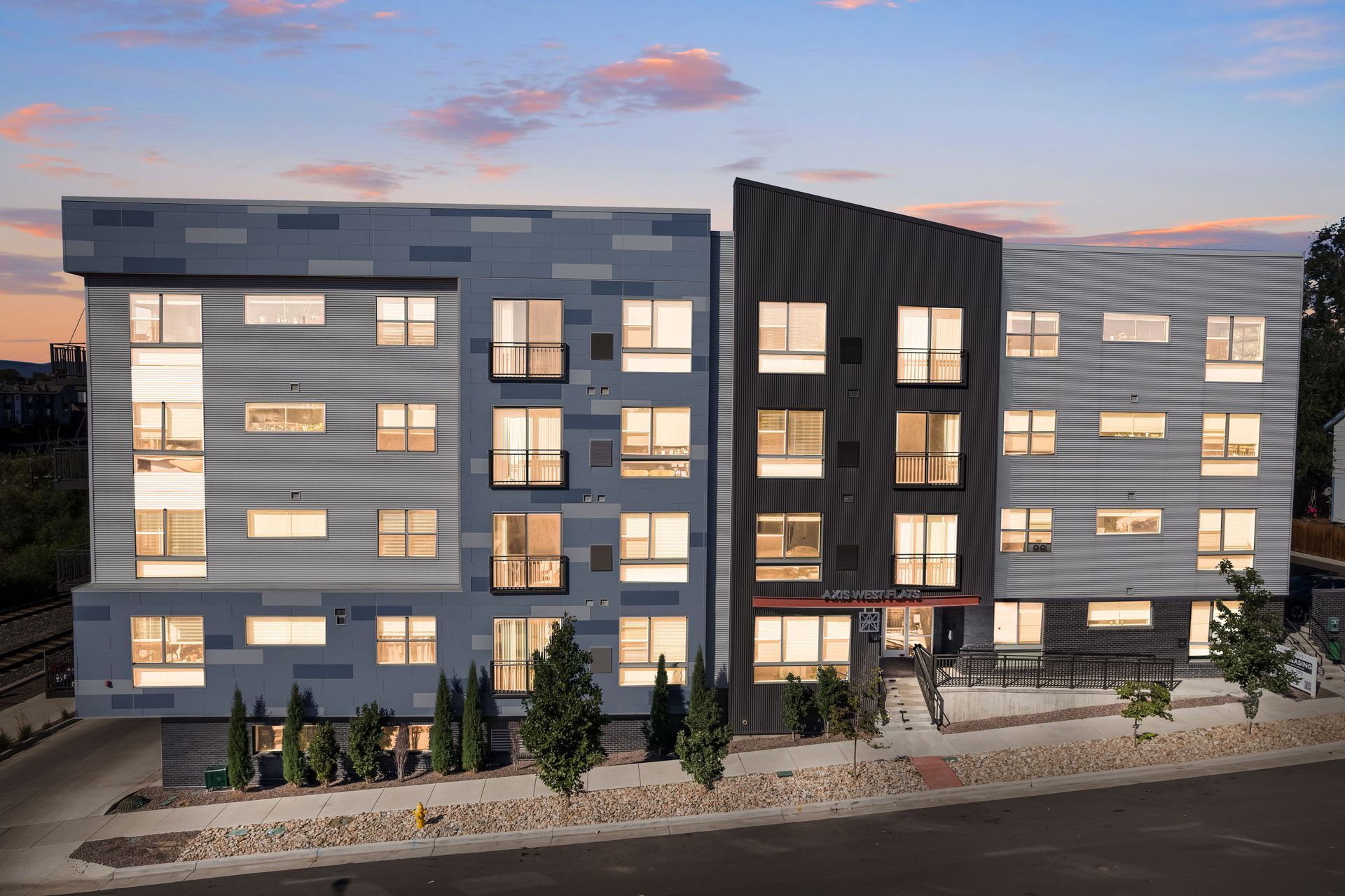 Modern multi-unit apartment building with geometric facades; evening twilight setting.