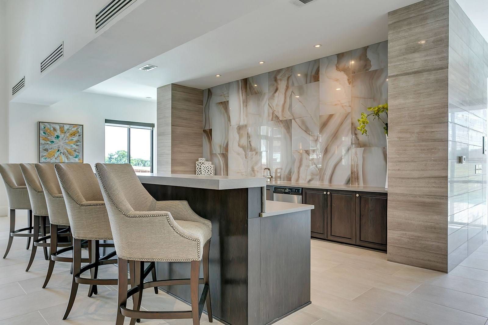 Bar area with marble accent wall, seating, and cabinetry.
