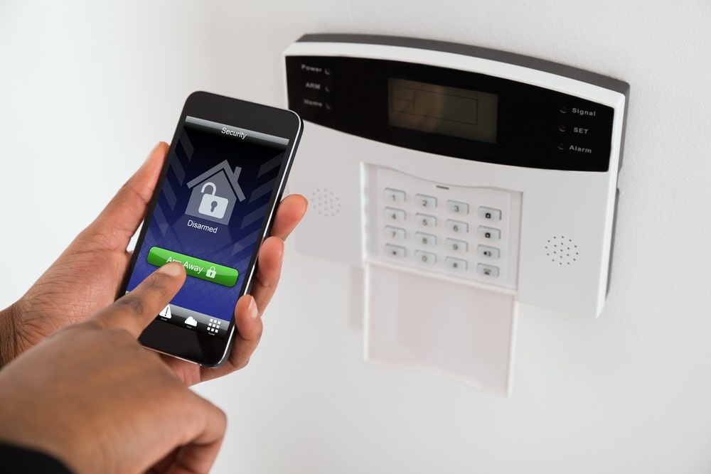 A Person Is Using A Smart Phone To Control A Security System — Troy Cummings Locksmith In Bungalow, QLD