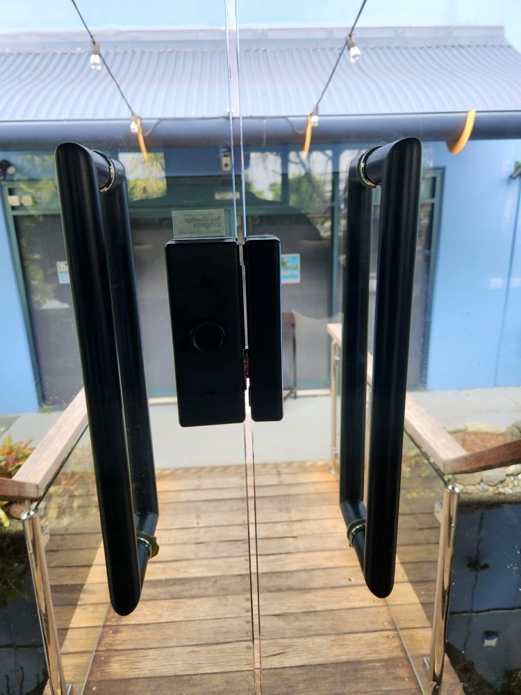 A Glass Door With Black Handles Is Open To A Wooden Deck — Troy Cummings Locksmith In Normanton, QLD