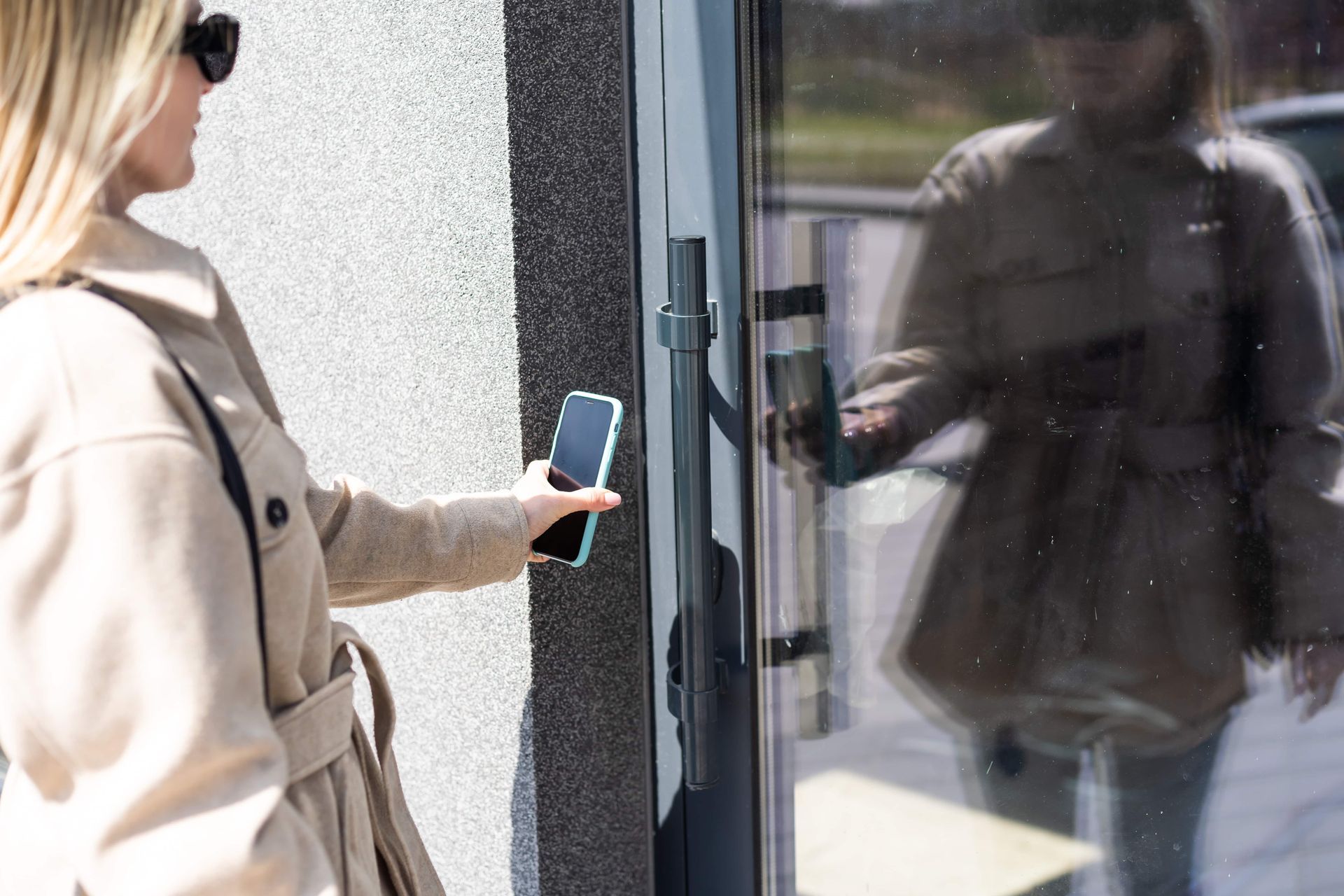A Woman Is Using A Smart Phone To Open A Door — Troy Cummings Locksmith In Mission Beach, QLD