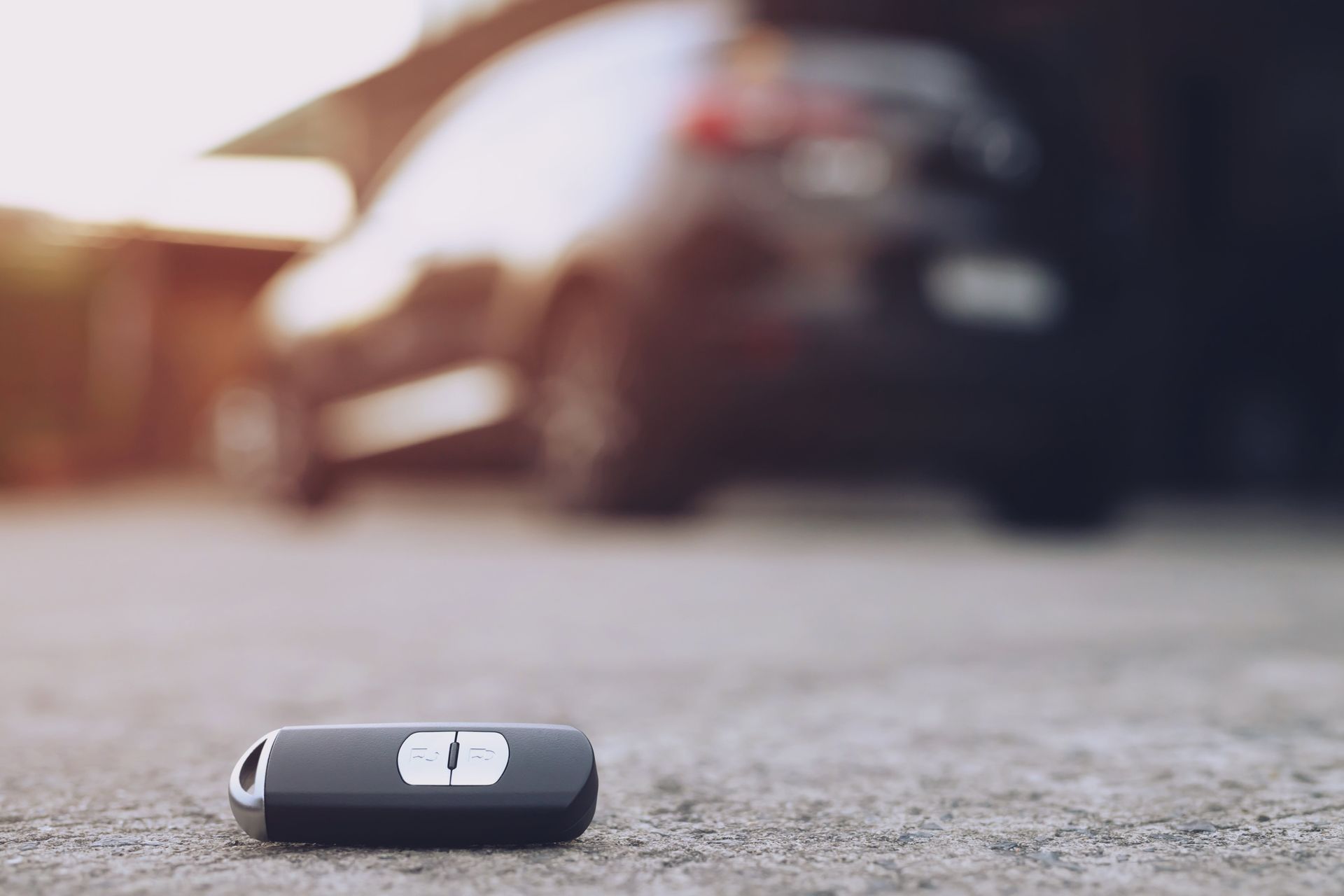 A Car Key Is Laying On The Ground In Front Of A Car — Troy Cummings Locksmith In Mission Beach, QLD