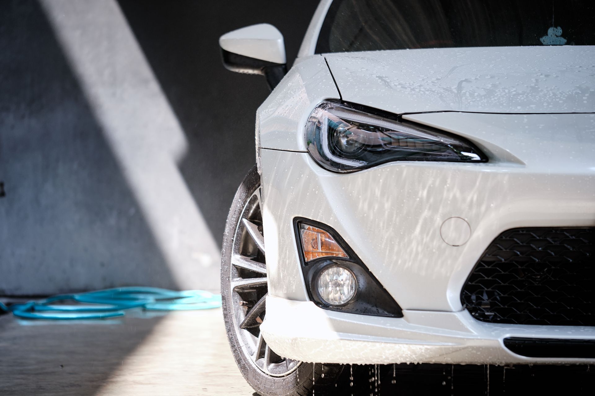 White sports car being washed; foamy suds on the hood.