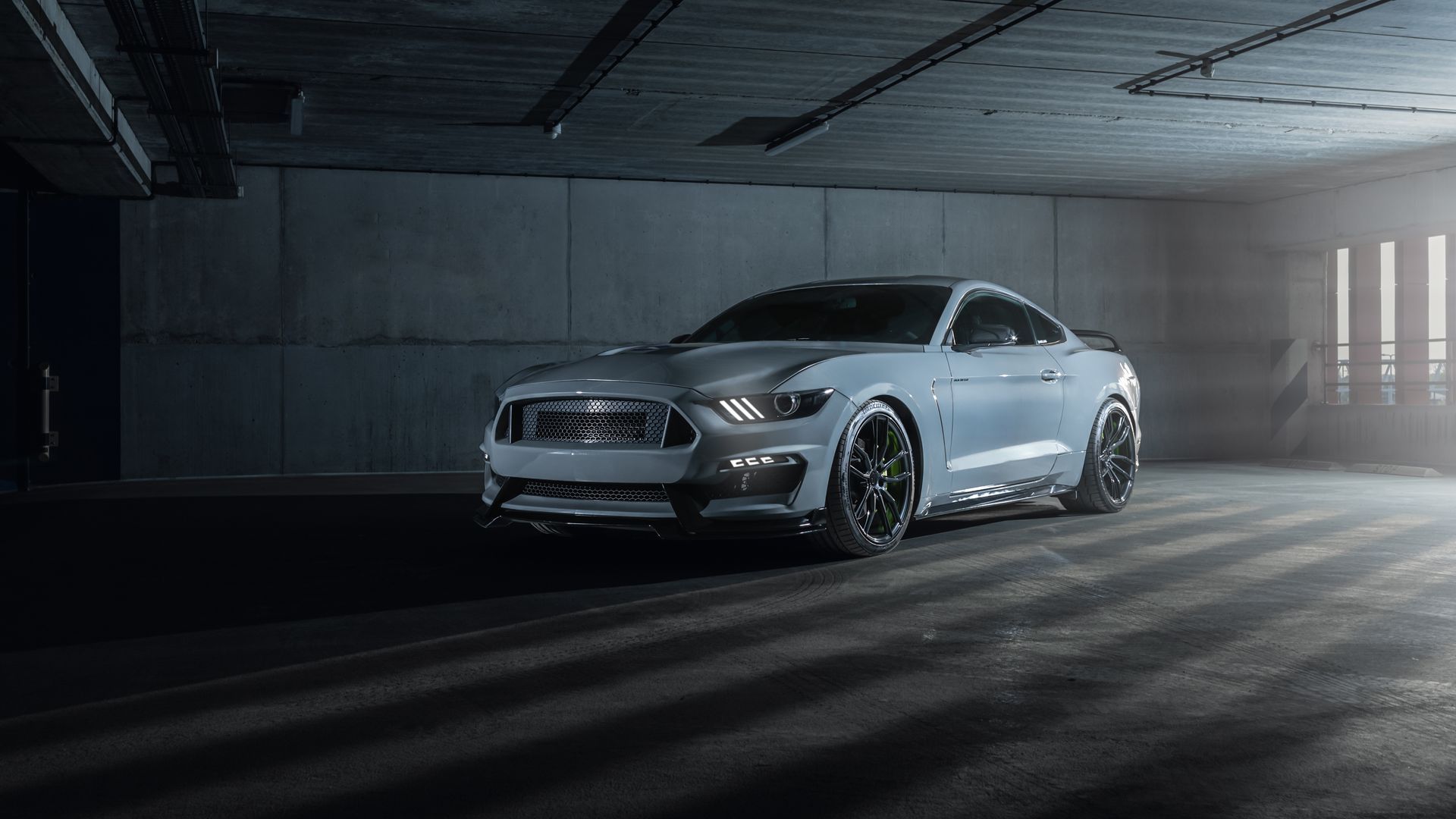 Gray Ford Mustang parked in a dimly lit industrial space.