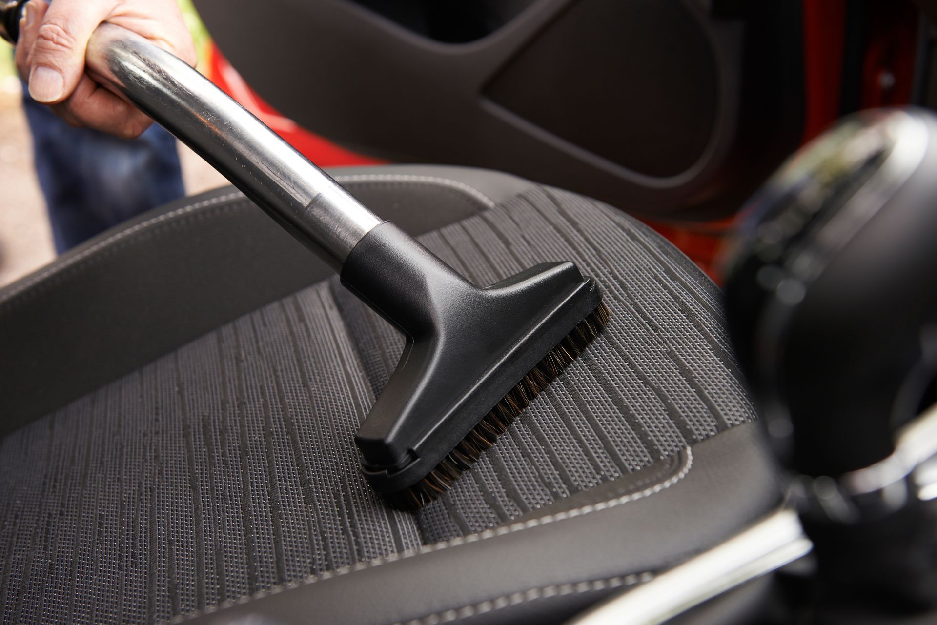 Vacuum nozzle cleaning a car seat.