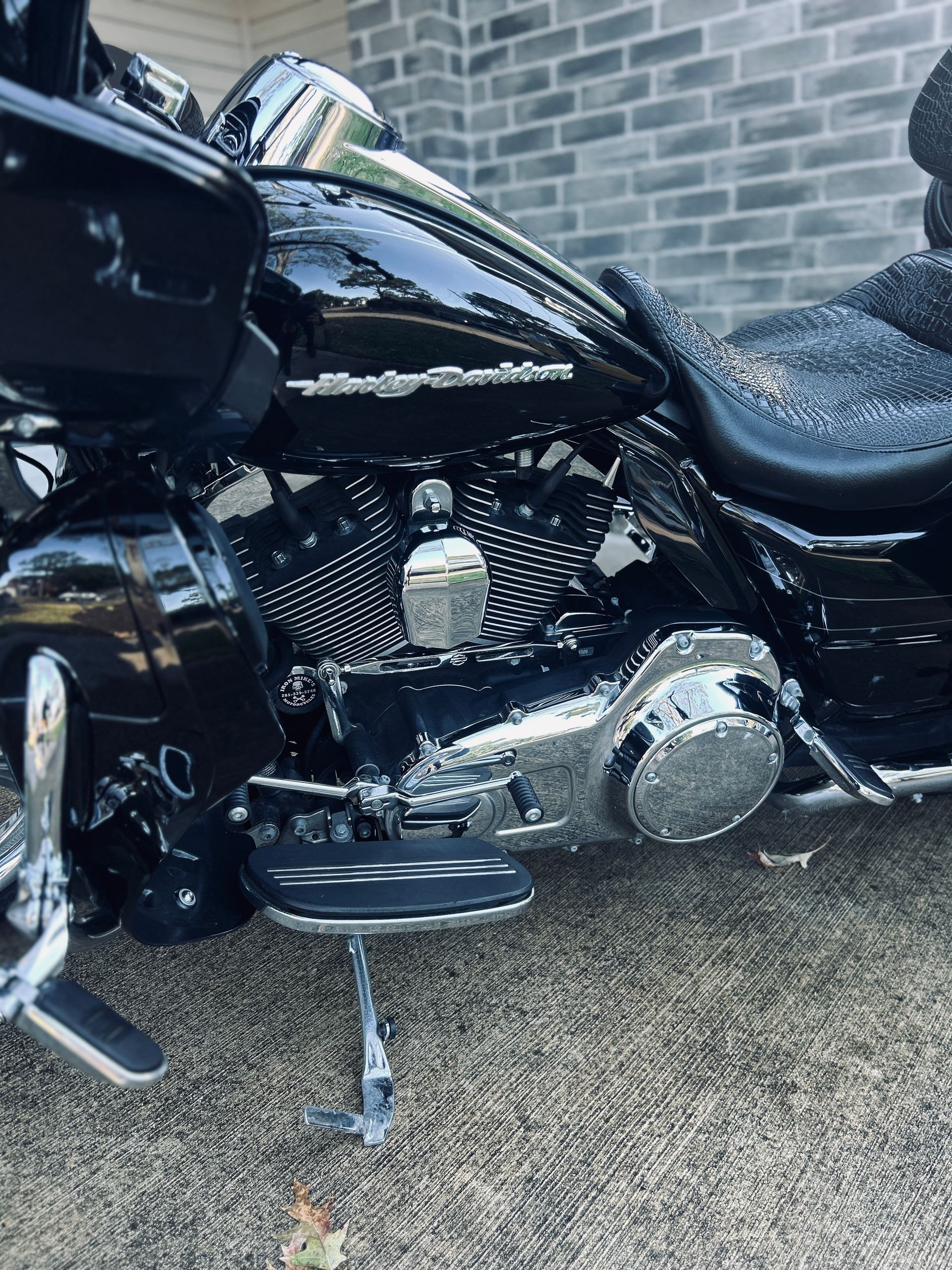 Black Harley-Davidson motorcycle parked on a concrete surface next to a brick building.