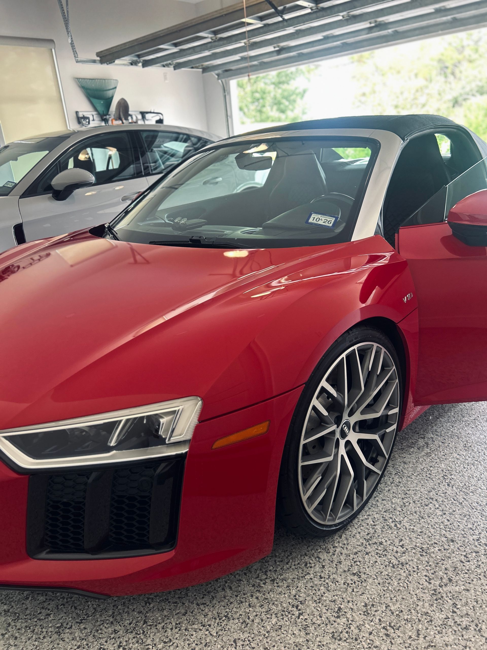 Red convertible Audi R8 with black top parked in a garage.