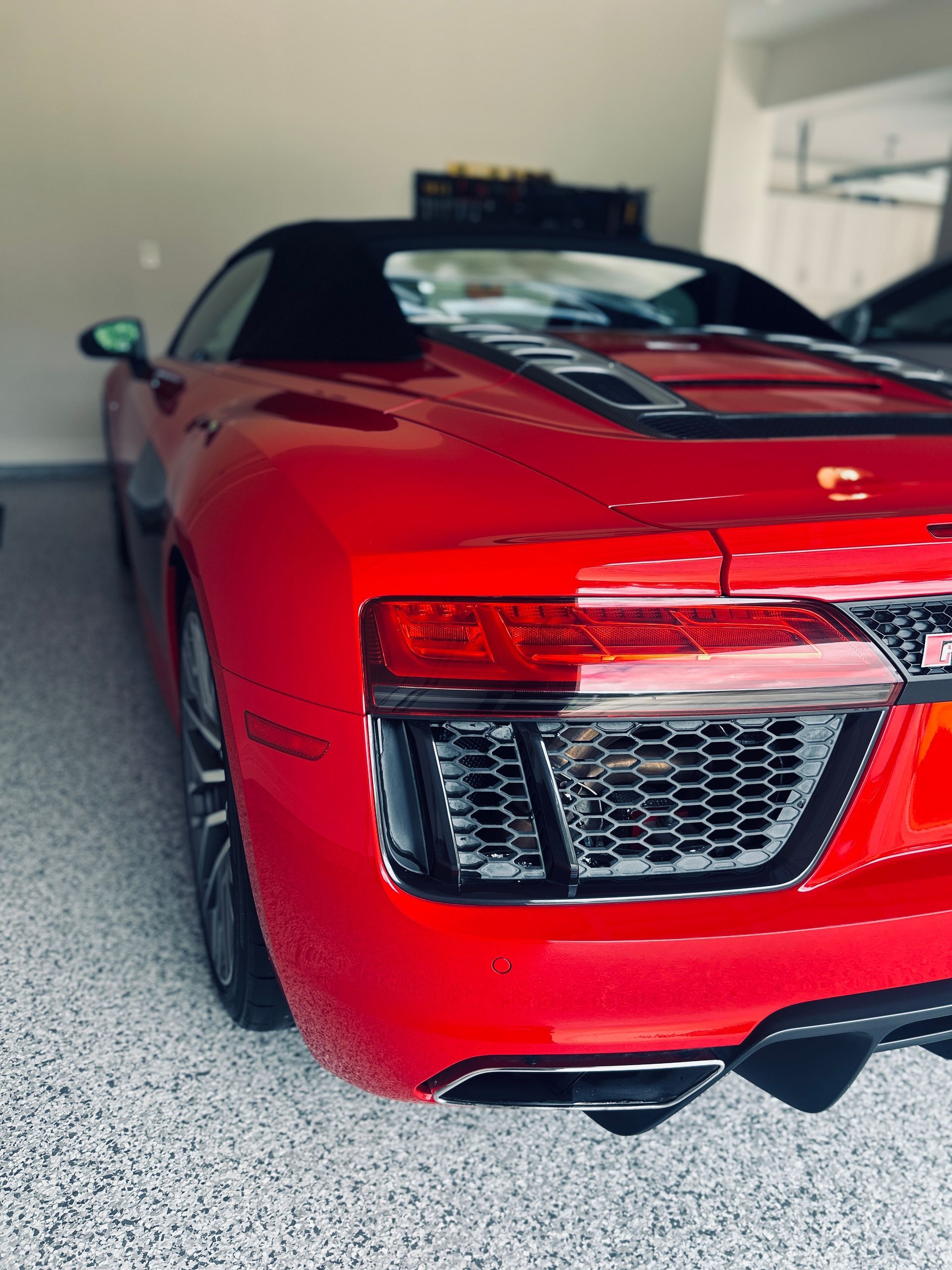 Red Audi R8 Spyder convertible parked in a garage.