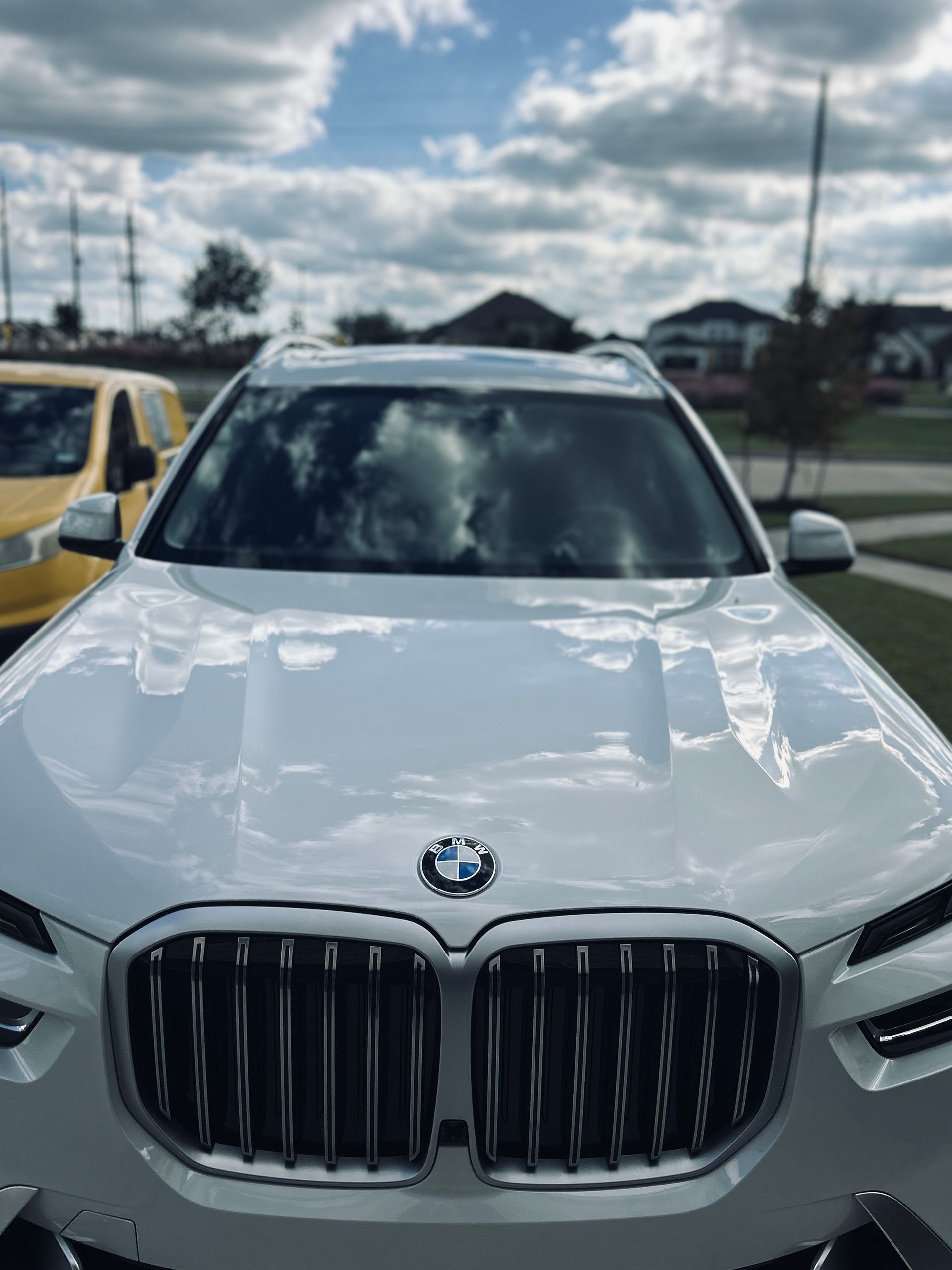 White BMW SUV parked outdoors under a cloudy sky.