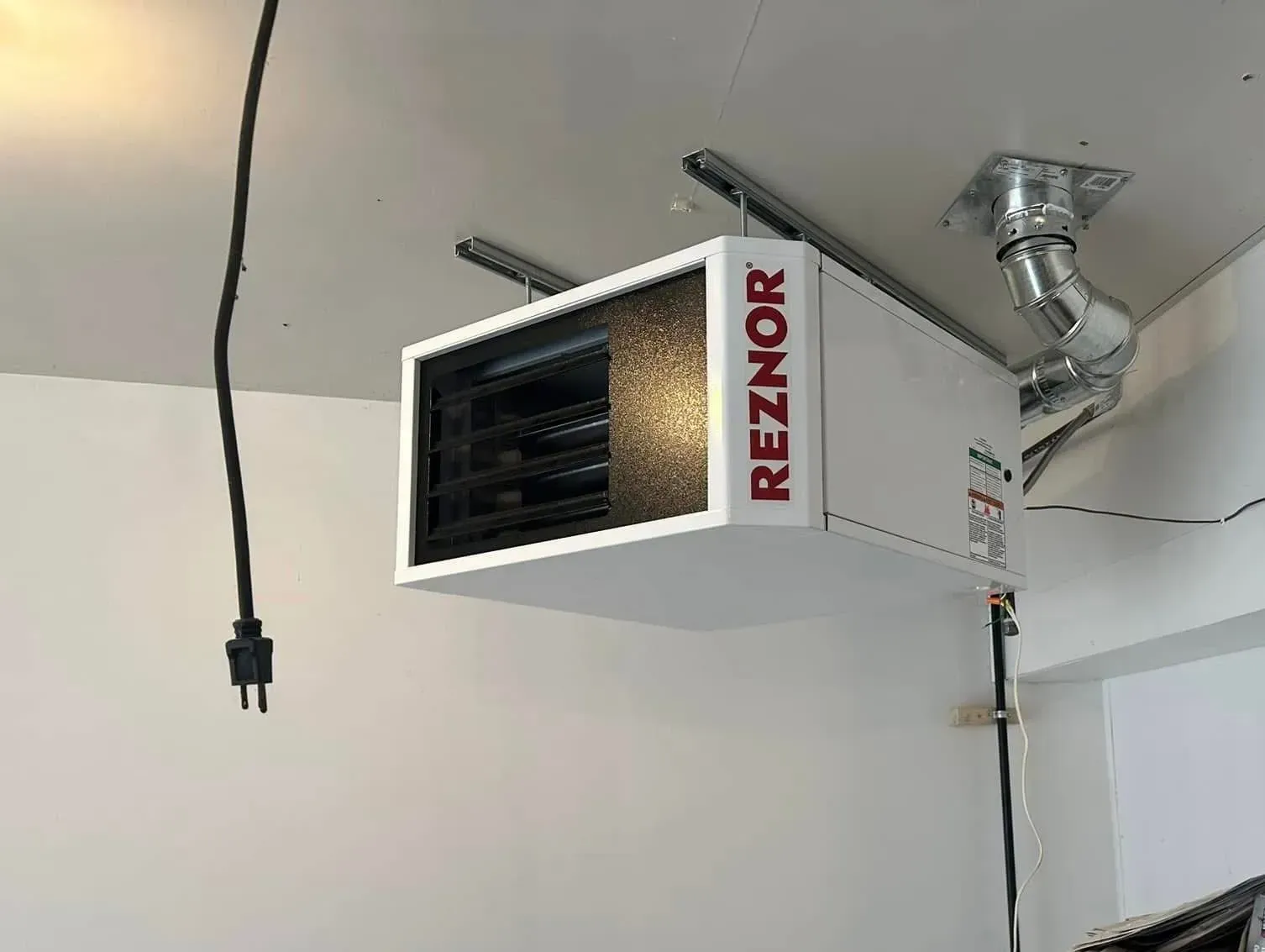 A heater is hanging from the ceiling in a garage.