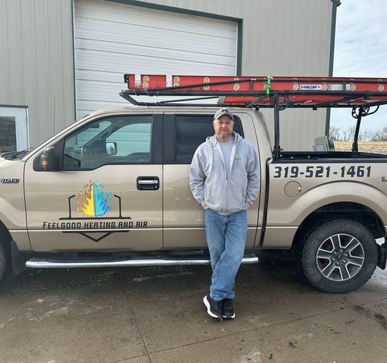 A man is standing in front of a truck that has the number 319-521-1461 on the back
