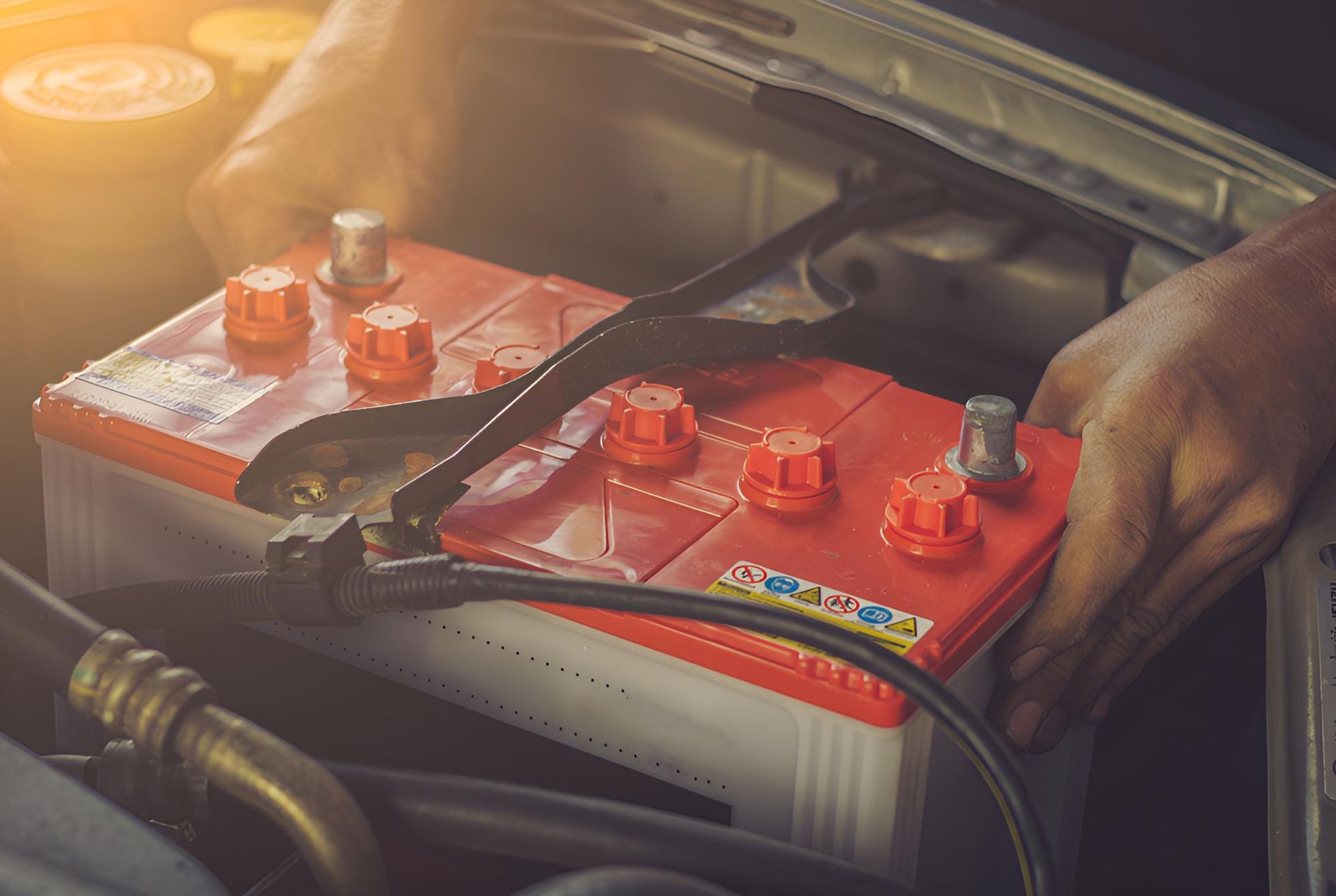 A Person is Plugging a Red Battery Into a Car — Cessnock Batteries In Rutherford, NSW