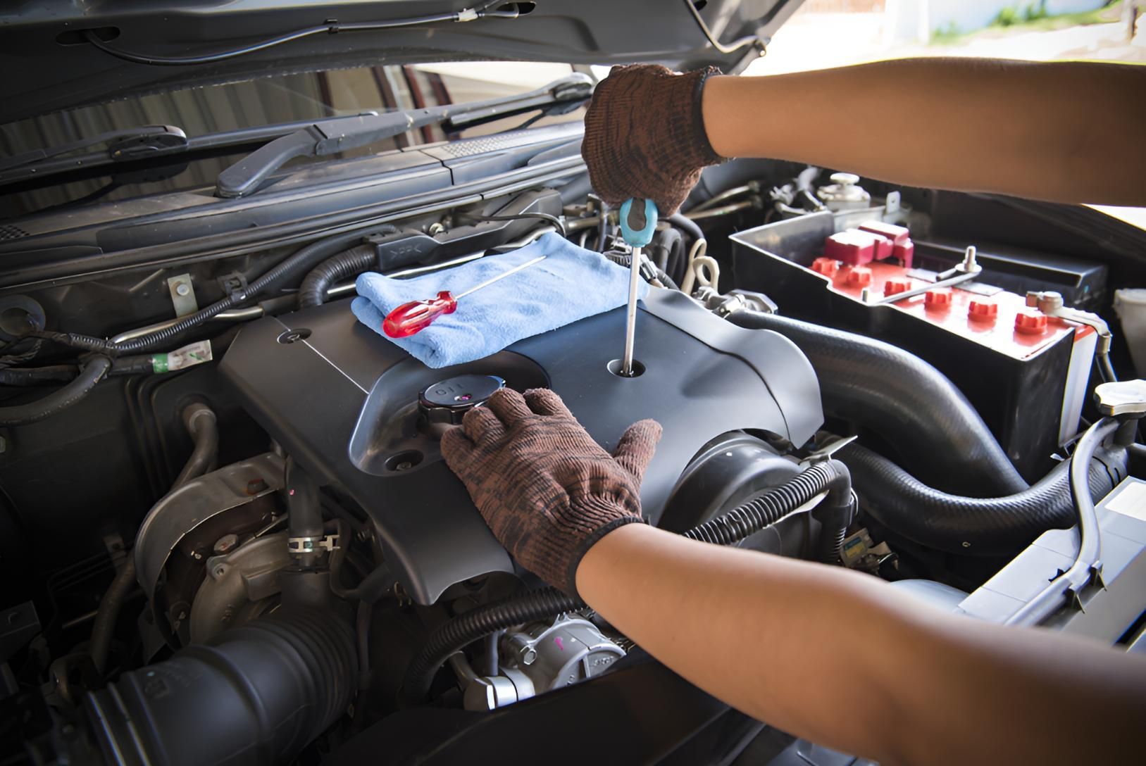 A Person is Working on the Engine of a Car With a Screwdriver — Cessnock Batteries In Kurri Kurri, NSW