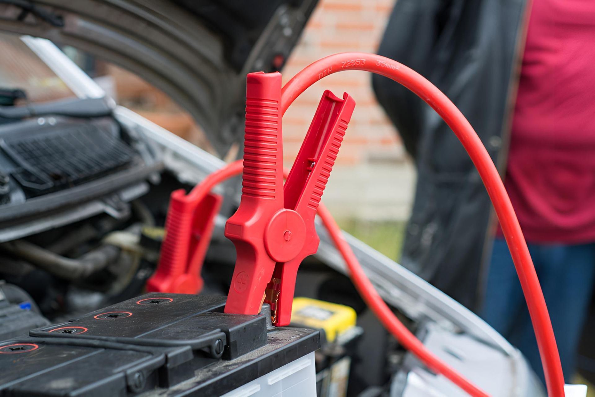 A Person is Charging a Car Battery With Jumper Cables — Cessnock Batteries In Rutherford, NSW