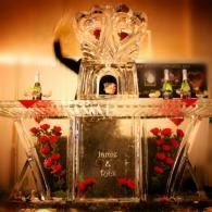 Decorative altar with crystal crown centerpiece, candles, and red floral arrangements in a warm-lit setting