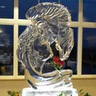 Clear ice sculpture of a man's head kissing a woman's forehead.
