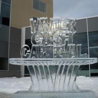 Ice sculpture spelling “Winter Carnival” in front of a building, with snow on the ground.