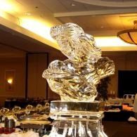 Glass ice sculpture centerpiece on a banquet table in a warmly lit dining room