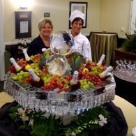 Chefs standing behind an ice sculpture buffet with fruit and crystal glasses at a formal event
