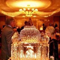 Elegant crystal chandelier glowing in a warmly lit banquet hall with guests in the background