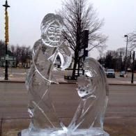 Clear ice sculpture of two people embracing in a park on an overcast day