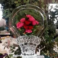 Clear glass vase with red roses against a leafy indoor background