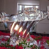 Clear glass abstract sculpture on a floral table centerpiece, with warm light reflections indoors