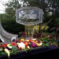 Clear glass memorial sign with flowers and greenery in a garden setting
